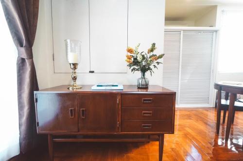 a wooden cabinet with a vase of flowers on it at Chez Moi Bangkok Private Executive Residence Sukhumvit 26 in Khlong Toei