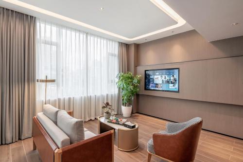a living room with a couch and chairs and a tv at Wellstay Hotel in Jianyang