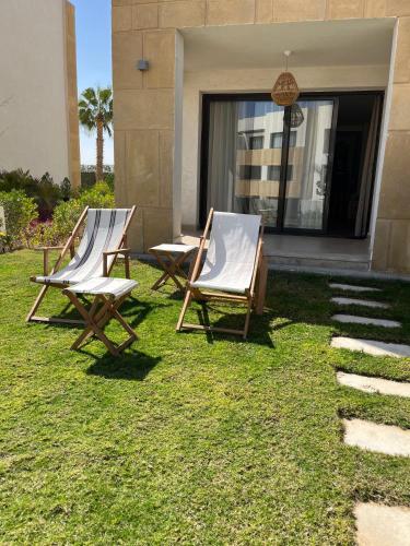two chairs sitting on the grass in front of a house at Superb Ground floor at Azha Ain Sokhna in Ain Sokhna
