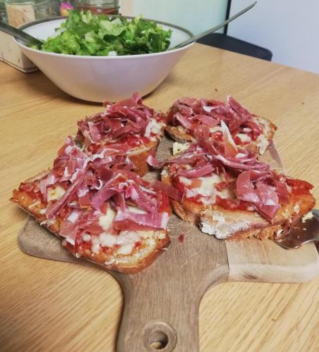 une tranche de pizza sur un plateau de découpe en bois avec salade dans l'établissement La Cantalienne du Saladou, à Mont-Chanson