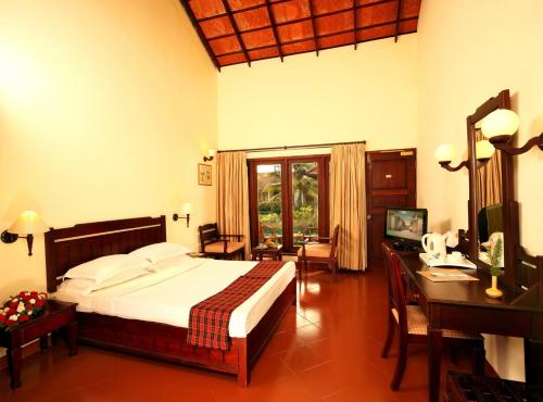 a bedroom with a large bed and a desk and a desk at Abad Whispering Palms in Kumarakom