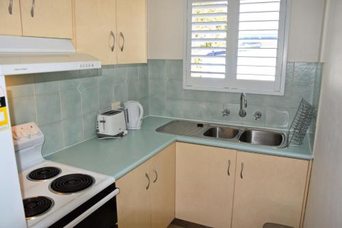 a small kitchen with a sink and a window at Seaspray no 5 - Bring your own linen. in South West Rocks