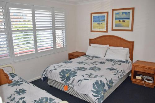 a bedroom with a bed and two windows at Seaspray no 5 - Bring your own linen. in South West Rocks