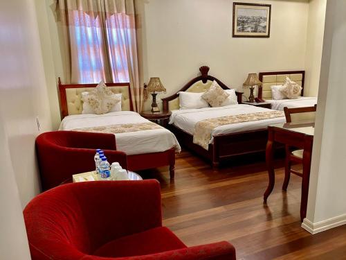 a hotel room with two beds and a chair at Khách sạn Sa Chi - Móng Cái in Móng Cái