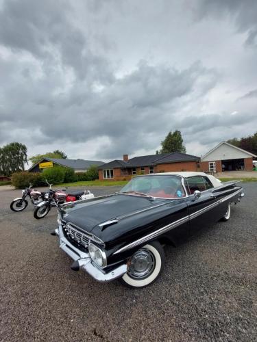a black car parked in a parking lot next to motorcycles at 55Tørring in Tørring