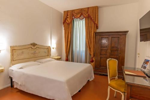 a bedroom with a large white bed and a desk at Hotel Machiavelli Palace in Florence