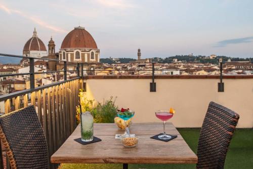 a wooden table with two glasses of wine on a balcony at Hotel Machiavelli Palace in Florence