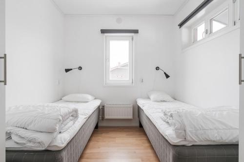 two beds in a room with white walls and a window at Kungsberget Åhus C8 in Botjärn