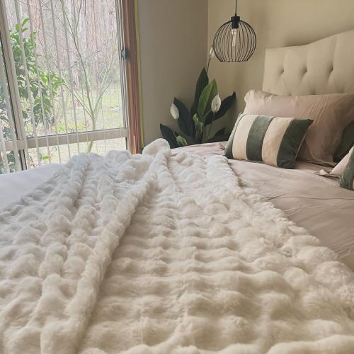 a large white blanket on a bed with a window at Greenwood Cottages in Tolmie