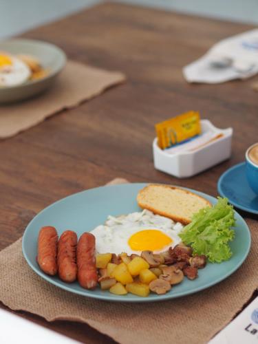 a plate of breakfast food with eggs sausage and bread at La Quoriena Botanical Villa & Cafe' in Labuan Bajo
