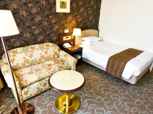 a hotel room with a bed and a couch at Kumamoto Hotel Castle in Kumamoto