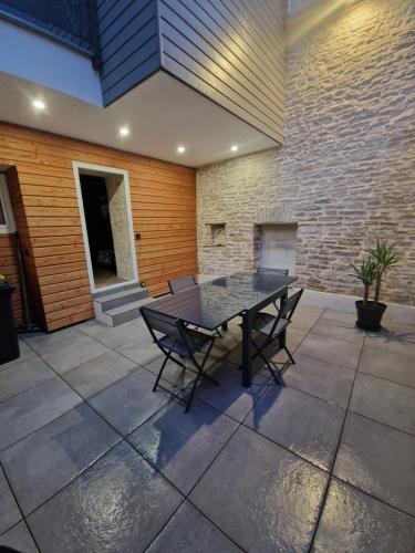 un patio avec une table et des chaises et un mur de briques dans l'établissement Charmante maison de ville, à Châtillon-sur-Seine