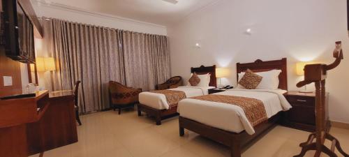 a hotel room with two beds and a television at ASHOKA INN in Trichūr