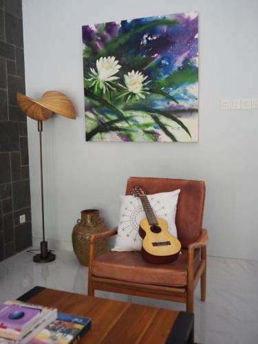 a guitar sitting on a chair in a living room at La Quoriena Botanical Villa & Cafe' in Labuan Bajo