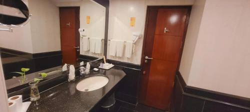 a bathroom with a sink and a large mirror at ASHOKA INN in Trichūr