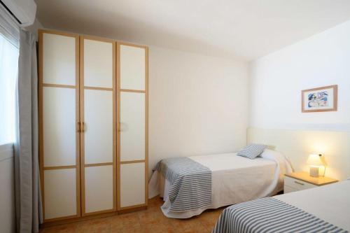 a bedroom with two beds and a closet at Villa Sa Calma in Port d'Addaia