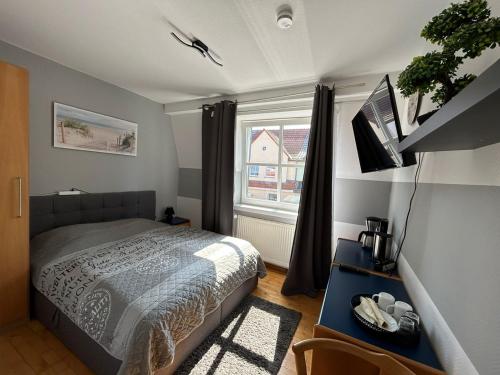 a bedroom with a bed and a tv and a window at Pension Stral-Sund UG in Stralsund