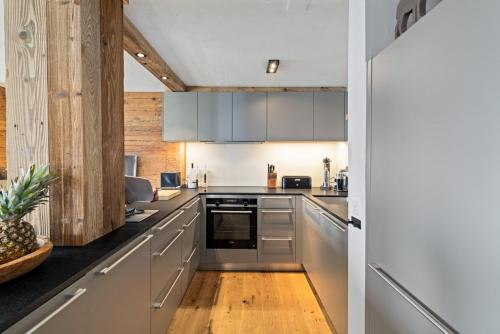 a kitchen with white cabinets and a wooden floor at Cabane de la Delege -Crans Montana- Amazing Views in Crans-Montana
