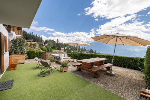 a patio with a picnic table and an umbrella at Cabane de la Delege -Crans Montana- Amazing Views in Crans-Montana