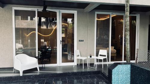 a store front with white chairs and a glass door at Waves By Jumbo Holidayz in Alibag