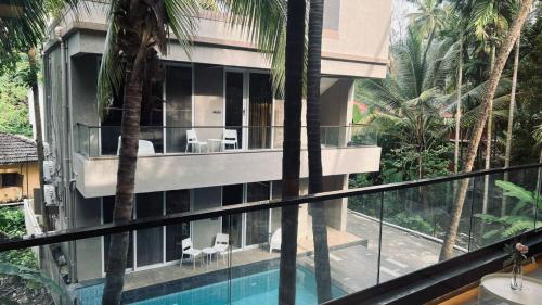 a house with a swimming pool and palm trees at Waves By Jumbo Holidayz in Alibag