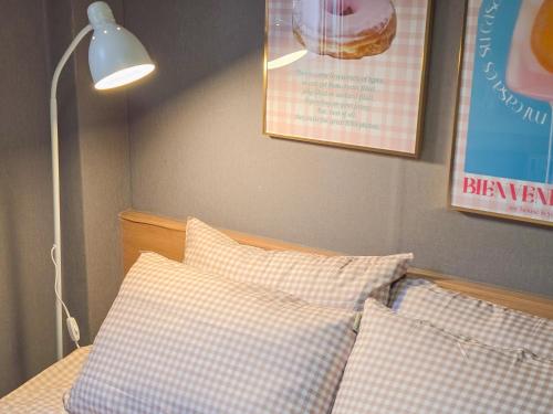 a bed with checkered pillows and a lamp on a wall at TOP Stay Guro digital complex in Seoul