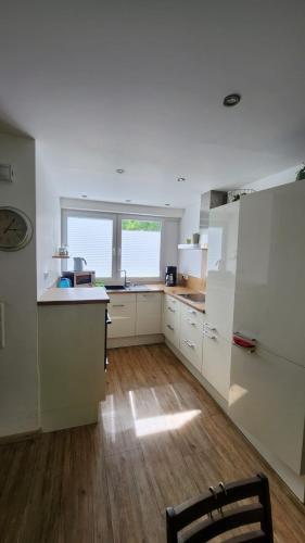 a kitchen with white cabinets and a wooden floor at Steinfeld - Klein, Schick & Gemütlich - 4you in Steinfeld