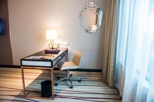 a desk with a lamp and a chair in a room at Dorsett Kuala Lumpur in Kuala Lumpur