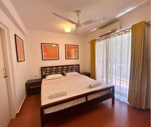 a bedroom with a bed and a large window at Jungle Hut-Annabelle's Beach Apartments at Bernard Simao,Calangute,Goa in Candolim