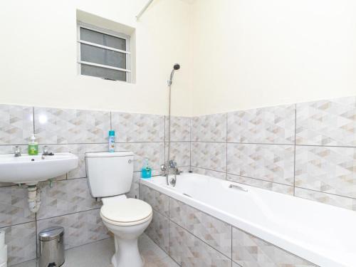 a bathroom with a toilet and a sink and a bath tub at Modern Seaview Apartment in Summerstrand