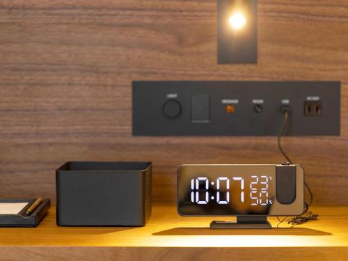 a clock sitting on a table next to a speaker at Kumamoto Hotel Castle in Kumamoto