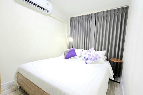 a bedroom with a white bed with purple pillows at ChiShi House Songkhla in Ban Bang Dan