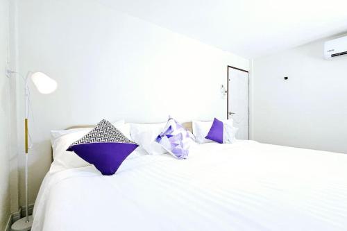 a white bed with purple pillows on it at ChiShi House Songkhla in Ban Bang Dan