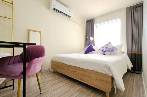 a bedroom with a bed and a purple chair at ChiShi House Songkhla in Ban Bang Dan