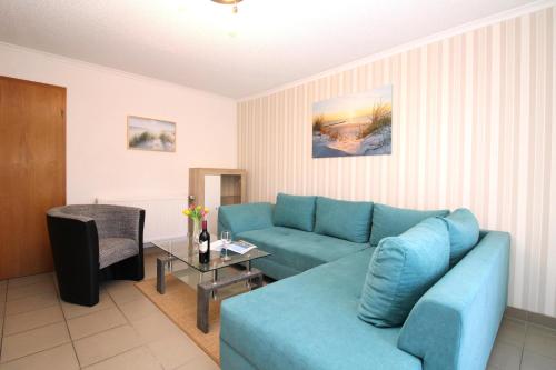 ein Wohnzimmer mit einem blauen Sofa und einem Tisch in der Unterkunft Ferienanlage Dröse, Haus 8a - Fewo 7 rolli-gerecht in Fulgen