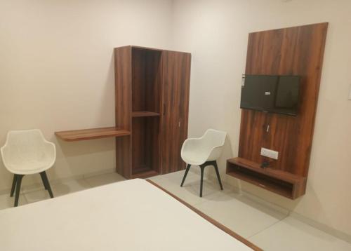 a bedroom with two chairs and a tv and a bed at Vaatsaly home's Rooms in Indore