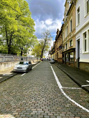 a cobblestone street with cars parked on the side at LaBed - Ferienwohnung auf Weingut mit privater Terrasse, zentral gelegen, gratis WLAN in Rüdesheim am Rhein