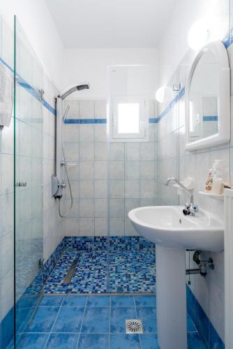 a blue and white bathroom with a sink and a shower at Sirines in Vlachata