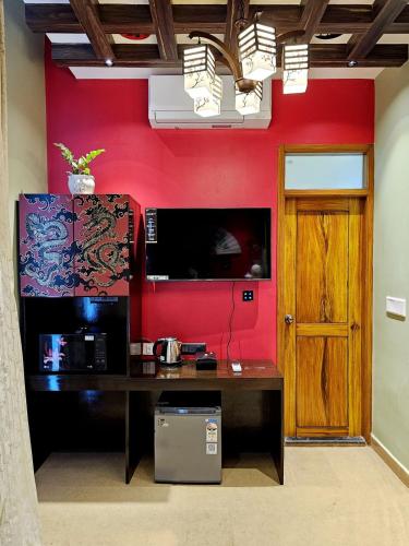 a room with a desk and a red wall at Blissful Stay, LUX Suites & Tint of Mint - 1 BHK Apartment, 5min Beach, Auroville Pondicherry in Kottakupam