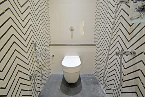 a bathroom with a toilet in a black and white patterned wall at Blissful Stay, LUX Suites & Tint of Mint - 1 BHK Apartment, 5min Beach, Auroville Pondicherry in Kottakupam