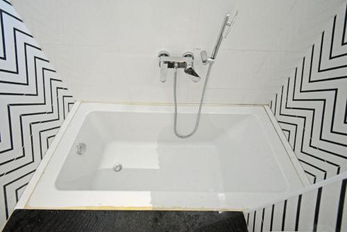 a white bath tub in a bathroom with black and white tiles at Blissful Stay, LUX Suites & Tint of Mint - 1 BHK Apartment, 5min Beach, Auroville Pondicherry in Kottakupam