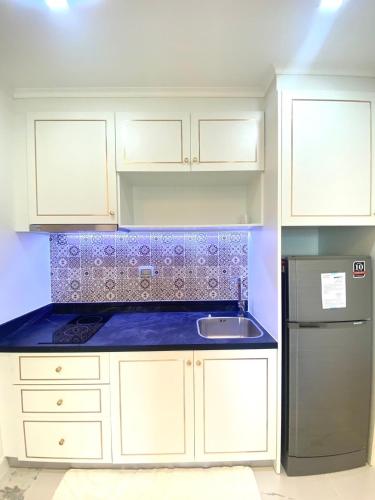 a kitchen with white cabinets and a sink and a refrigerator at Empire Tower Pattaya Jomtien Beach in Jomtien Beach