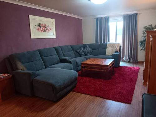 a living room with a blue couch and a table at The Quiet Rose in Lithgow