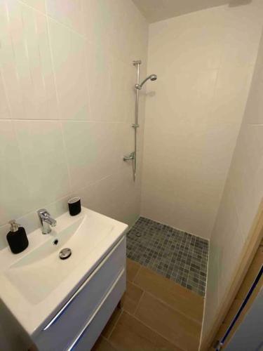 a white bathroom with a sink and a shower at Maison à 300m de la mer avec 2 chambres in Lion-sur-Mer