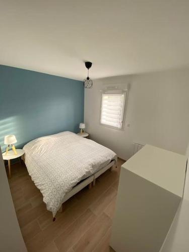 une chambre avec un lit blanc et une fenêtre dans l'établissement Maison à 300m de la mer avec 2 chambres, à Lion-sur-Mer