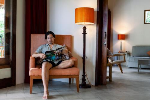 a man sitting in a chair reading a magazine at Darmada Eco Resort in Sidemen