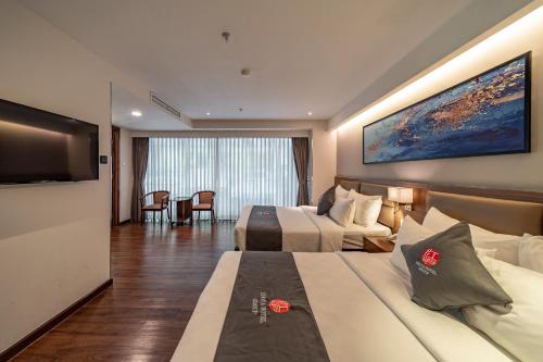 a hotel room with two beds and a flat screen tv at Edoya Hotel Ben Thanh in Ho Chi Minh City