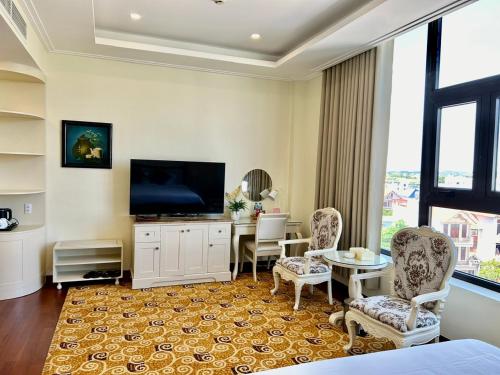 a living room with a television and a table and chairs at Khách sạn Sa Chi - Móng Cái in Móng Cái