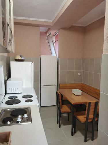 a kitchen with a table and a white refrigerator at Bar-Apartman 2 in Bar