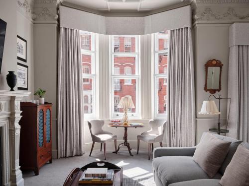 a living room with a couch and a table in front of a window at The Chelsea Townhouse by Iconic Luxury Hotels in London